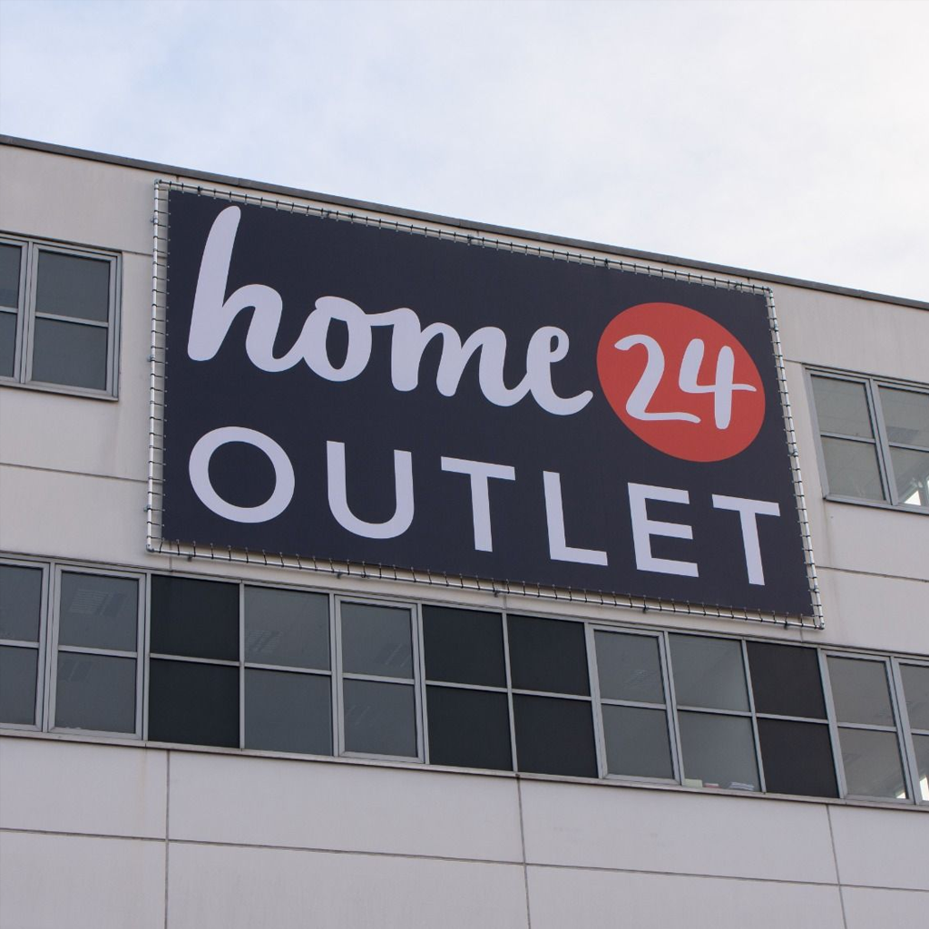 Großformatiges Stoffbanner im Fassadenrahmen an einer Gebäudewand.