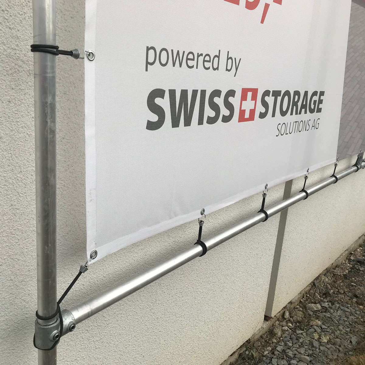 Detail: Unterkante eines Banners mit mehreren Spannfixen gleichmäßig verteilt