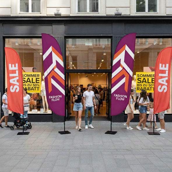 Beachflags mit SALE-Motiv und Markenlogo „Fashion Flow“ im Eingangsbereich eines Modegeschäfts – prominente Platzierung zur Bewerbung von Sonderangeboten.
