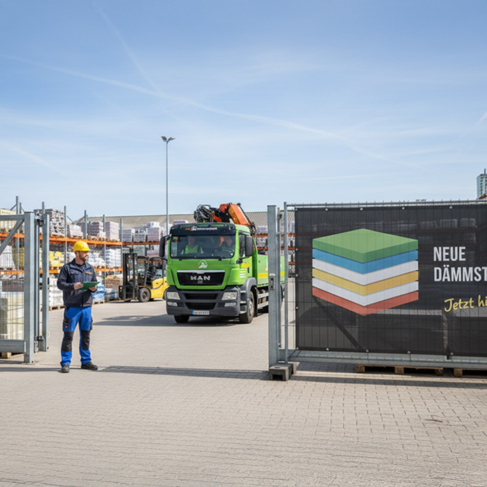 Bauzaunbanner am Eingang des Baustoffhandels bei Sonnenschein