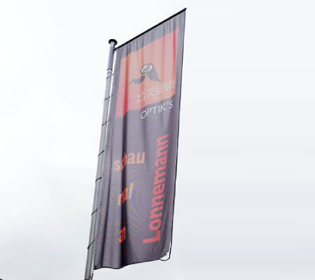 Fahne am Mast mit ausgerissenem Saum – Beispiel für Fahnenverschleiß, Tipps für längere Haltbarkeit